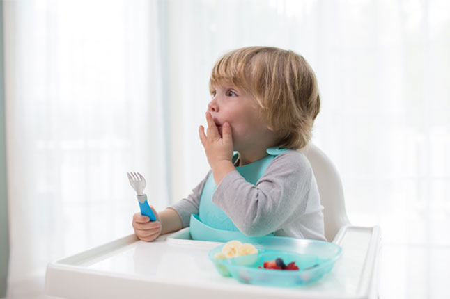 Toddler with a divided plate, soft-grip spoon and fork